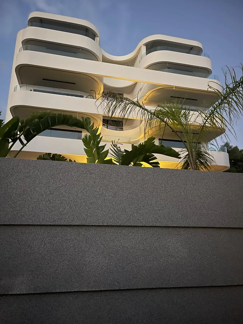 Glyfada Residences · Curved balconies and planted frontage in evening light
